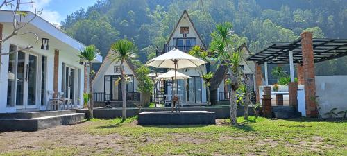 a house with an umbrella in front of it at Batur Homestay and Lodge in Bangli