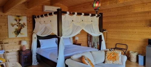 a bedroom with a canopy bed and a couch at Healing Garden Retreat Tallebudgera Valley "The Uluwatu" in Gold Coast