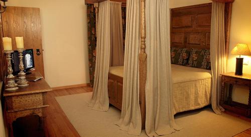 a bedroom with a bed with curtains and a table at Hotel Real d Obidos in Óbidos