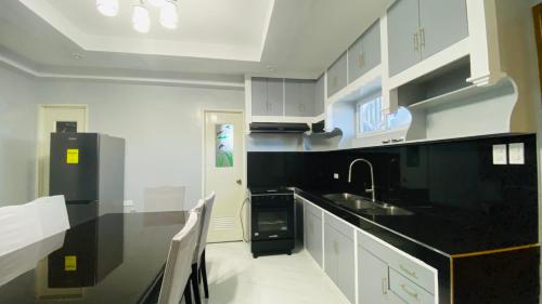 una cucina con mobili bianchi e un piano di lavoro nero di VillaMar Ramos Resort a Lingayen