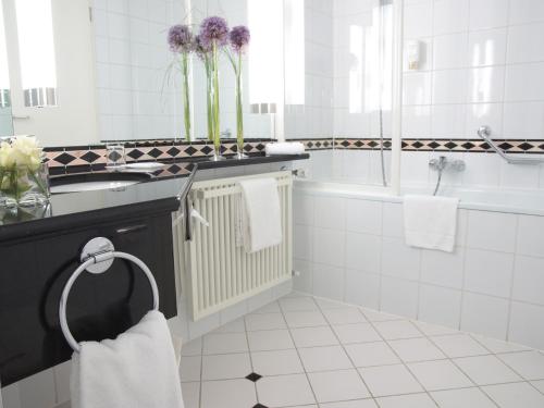 a white bathroom with a sink and a bath tub at Atlanta Boardinghouse Leipzig in Leipzig