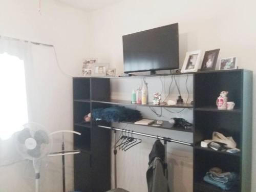 a room with a shelf with a tv and a fan at Muy Linda casa a 1 cuadra de terminal de Omnibus in Montevideo