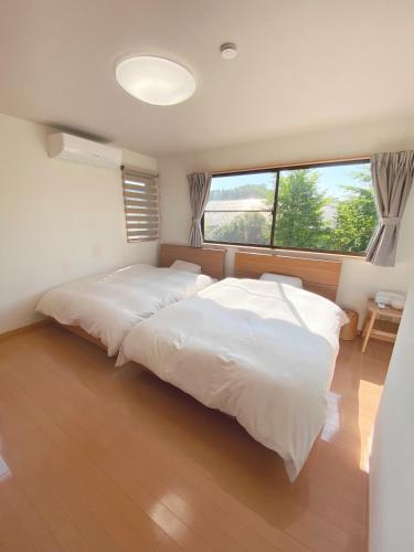 Un dormitorio con una gran cama blanca y una ventana. en ととのいのいえ千葉富津, en Minato