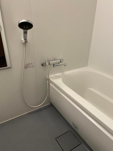 a bath tub with a hose next to a white tub at Ryokan Miyoshi in Nagoya