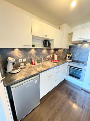 une cuisine avec des armoires blanches et un plancher en bois dans l'établissement Évasion douillette, charmant 2 pieces 20 minutes de Strasbourg, à Erstein