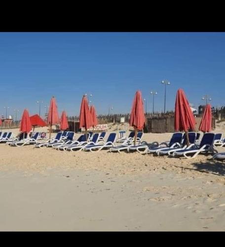 a group of chairs and umbrellas on a beach at شاليه للإيجار بقريه اكوا فيو الساحل الشمالي in El Alamein