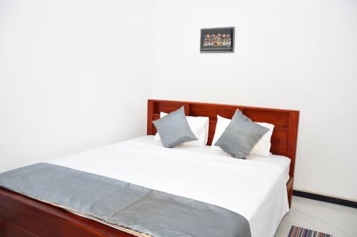 a bedroom with a bed with white sheets and blue pillows at Sasanda Villa and Yala Safari Place in Tissamaharama