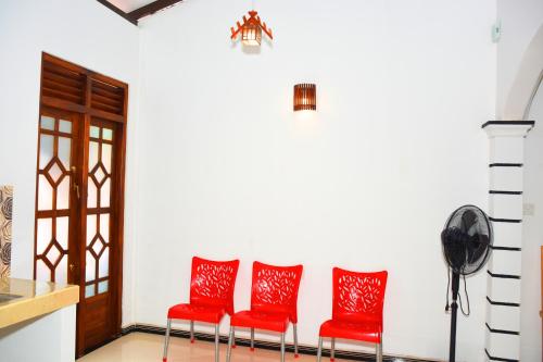 three red chairs in a room with a door at Sasanda Villa and Yala Safari Place in Tissamaharama