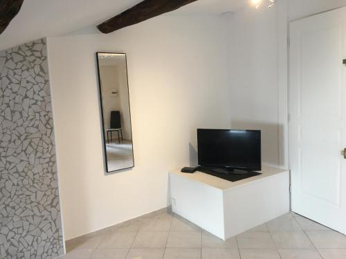- une télévision sur un mur blanc avec un miroir dans l'établissement Épices 1 au cœur du centre ville historique de Serignan, à Sérignan