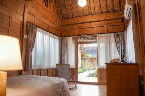 une chambre avec un lit, une télévision et une fenêtre dans l'établissement Ijen Estate Resort And Villa, à Banyuwangi