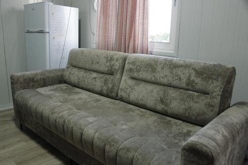 a couch sitting in a living room next to a refrigerator at Mahane in Tirana