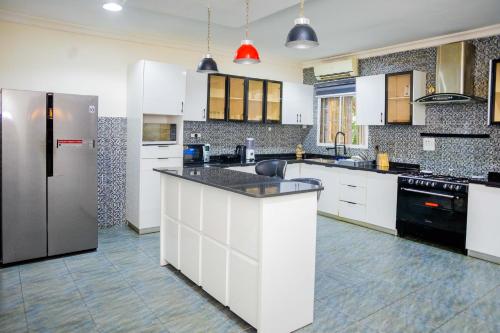 a kitchen with white cabinets and a stainless steel refrigerator at LEKKI SECRET MANSION 'n' SWIMMING POOl in Aja