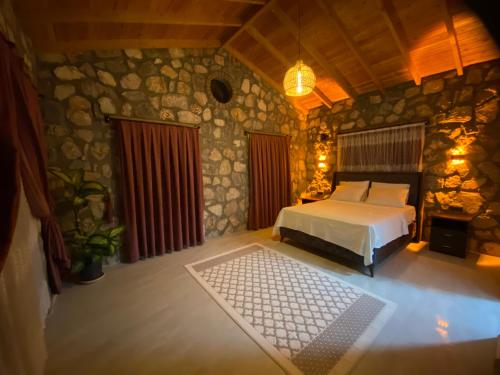 a bedroom with a bed and a stone wall at Luxury Stone House With Turkish Hamam, Sauna, İndoor and Outdoor Pool in Fethiye in Mugla