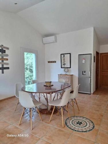 une salle à manger avec une table et des chaises blanches dans l'établissement Gîte du chêne vert 5 personnes, à Saint-Quentin-la-Poterie