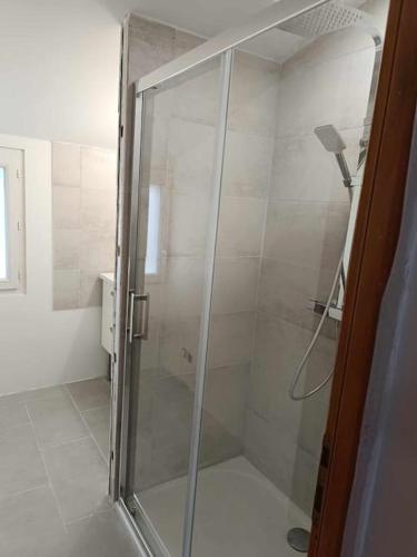 une douche avec une porte vitrée dans une salle de bain dans l'établissement Gîte du chêne vert 5 personnes, à Saint-Quentin-la-Poterie