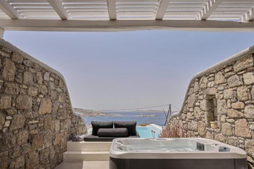 a room with a bath tub in a stone wall at Ovea Mykonos in Mikonos