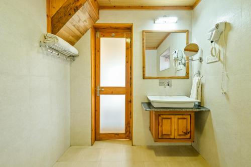 a bathroom with a sink and a mirror at WoodVista Cottages By Jomotel in Shimla