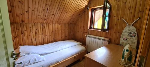a small bed in a wooden room with a window at Holiday Home Stevas in Žabljak