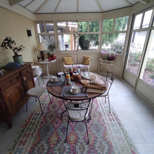 een woonkamer met een tafel, stoelen en ramen bij L'Acacia in Bergerac