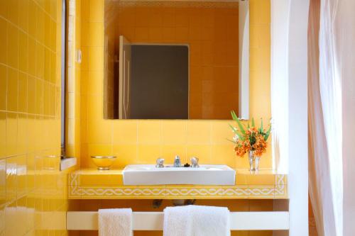 Baño amarillo con lavabo y espejo en Lageado Park, en Albufeira