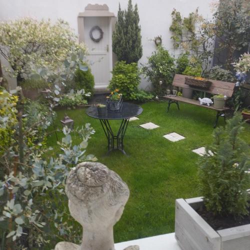 un jardin avec une statue, une table et un banc dans l'établissement Le Clos des Mouettes, à Calais