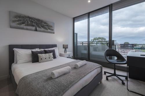 a bedroom with a bed and a desk and a chair at Brand New 2br2ba Caulfield Parkbalcony Poolgym in Melbourne