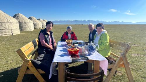 a group of people sitting at a table in a field at Yurt Camp Ali-Nur, Lake Song-Kul , Kyrgyzstan, Юрточный лагерь Али Нур, на берегу озера Сон Кол in Naryn
