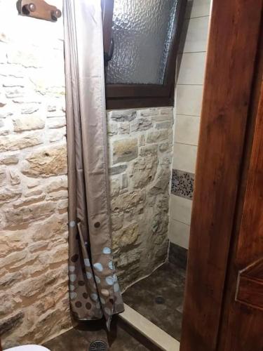 a shower in a bathroom with a stone wall at Παραδοσιακη οικια in Flátsia