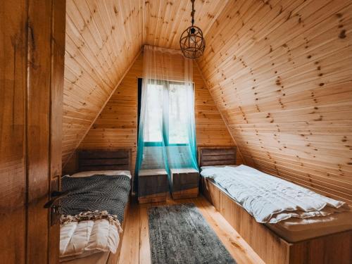 two beds in a wooden room with a window at KALOHOUSE in Dandalo