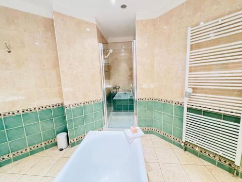 La salle de bains est pourvue de murs carrelés verts et d'une douche. dans l'établissement Sainte-barbe T4, Billard à 2 pas du château fort, à Sedan