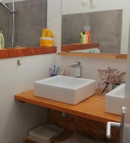 une salle de bain avec un lavabo blanc sur un comptoir en bois dans l'établissement Maison bord de mer, à La Tremblade