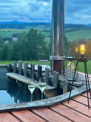 two glasses of white wine sitting on a wooden deck at Glamping Salaš in Mochtín