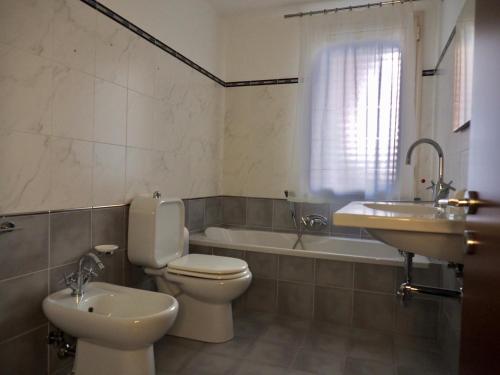 Un baño con inodoro, lavabo y bañera. en Golden House Holiday, en Belpasso