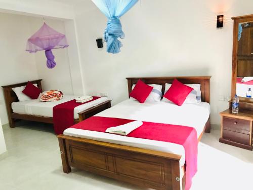 a bedroom with two beds with red pillows at Ella Jayamali Holiday Pavilion in Ella