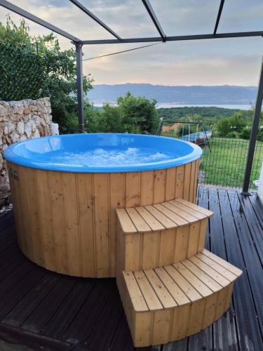 a hot tub on a deck with a bench around it at Holiday Home with Sea View in Vrbnik