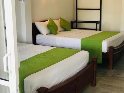 two beds with green and white sheets in a room at Ella Jayamali Holiday Pavilion in Ella