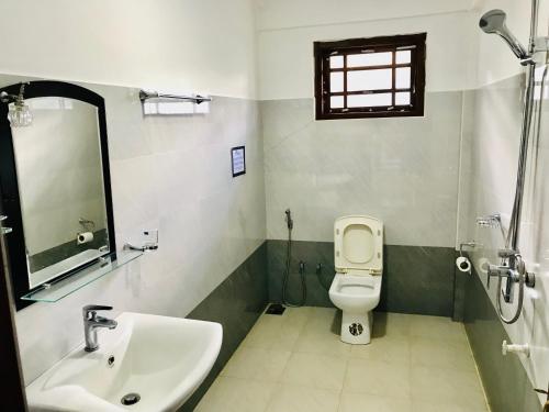 a bathroom with a sink and a toilet and a mirror at Ella Jayamali Holiday Pavilion in Ella