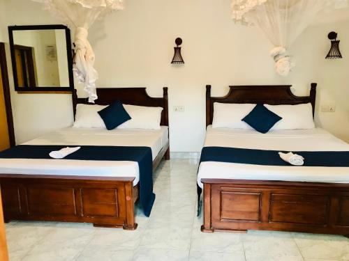 a bedroom with two beds and a mirror at Ella Jayamali Holiday Pavilion in Ella