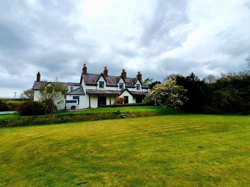 a white house with a grass field in front of it at Bryansford Cottage in Castlewellan
