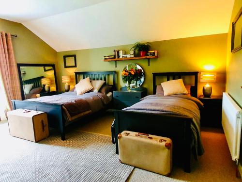 sypialnia z dwoma łóżkami i walizką w obiekcie Bryansford Cottage w mieście Castlewellan