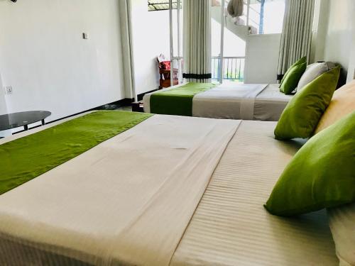 two large beds in a room with green pillows at Ella Jayamali Holiday Pavilion in Ella