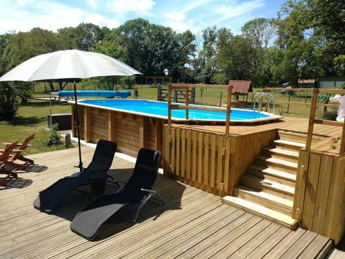 a wooden deck with a swimming pool and an umbrella at La Bulle des alpagas in Herry