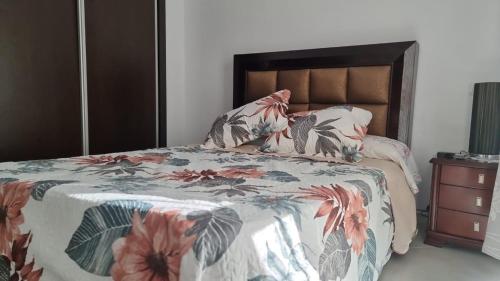 a bedroom with a bed with a floral comforter at Résidence Lilia Al Jabal M’diQ in M'diq