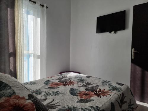 a bedroom with a bed with a flowered blanket and a window at Résidence Lilia Al Jabal M’diQ in M'diq