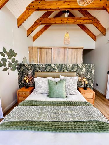 a bedroom with a large bed with green pillows at Thalassophile Beach House - Heated Pool in St. Helena Bay