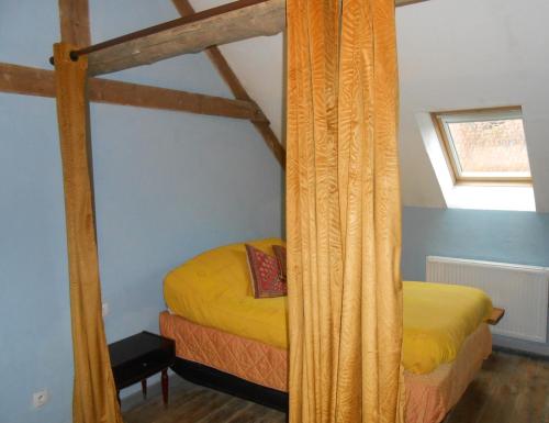 a bedroom with a canopy bed with yellow sheets at 14 rue de Monteville in Coupelle-Vieille