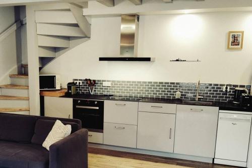une cuisine avec des armoires blanches et un canapé dans une pièce dans l'établissement Jolie maison basque entre mer et montagne, à Hendaye