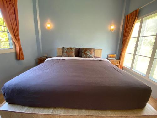 a large bed in a bedroom with two windows at Green Tree Cottage 4 in Klong Muang Beach