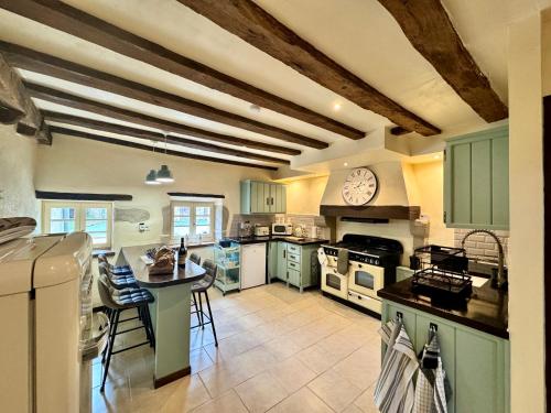 une cuisine avec des placards verts et une horloge murale dans l'établissement Les Trois Cheminees, à Fromental