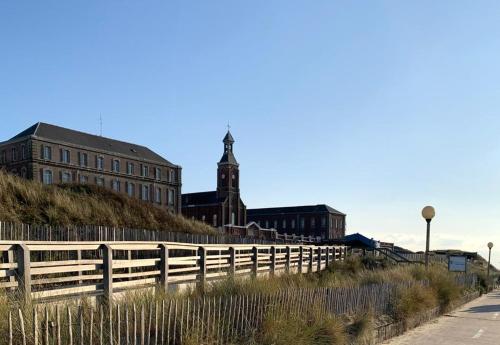 una recinzione di fronte a un edificio con torre dell'orologio di GITE du Phoque Gris a Berck-sur-Mer